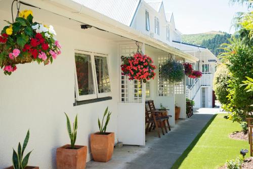 a white house with flowers on the side of it at Waimarie on Riverside Motel & Apartments in Nelson