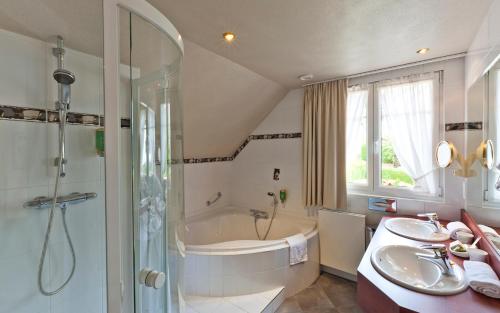 a bathroom with a tub and a sink and a shower at Hotel Restaurant Auberge Metzger in Natzwiller