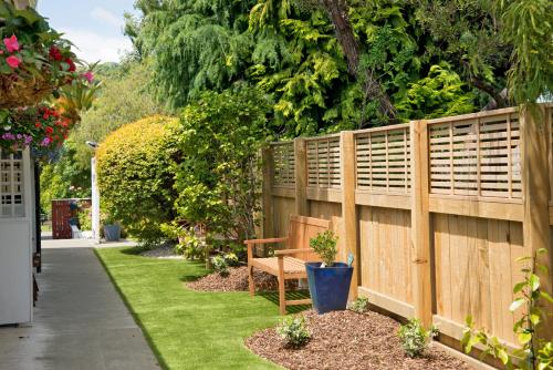 a wooden fence with a bench in a garden at Waimarie on Riverside Motel & Apartments in Nelson