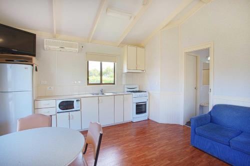 a kitchen with a table and a blue couch at Discovery Parks - Warrnambool in Warrnambool