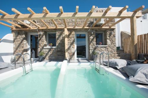 a swimming pool with a wooden pergola at Merchia Bay Villas Mykonos in Merchia Beach
