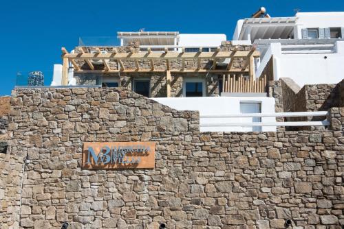 a sign on the side of a stone wall with a building at Merchia Bay Villas Mykonos in Merchia Beach