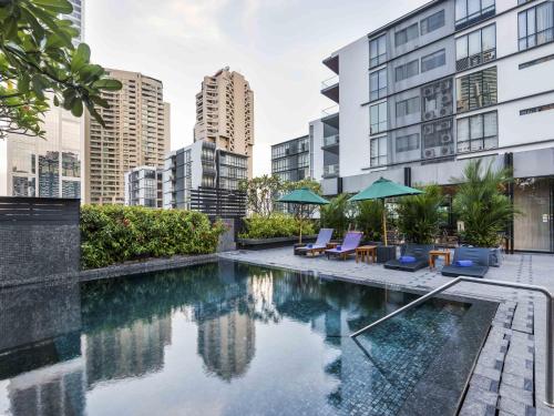 a pool with chairs and umbrellas on a building at Maitria Hotel Sukhumvit 18 Bangkok – A Chatrium Collection in Bangkok