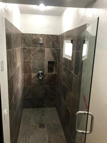 y baño con ducha y azulejos marrones. en Hotel Raga Inn en Tamasopo