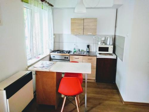a small kitchen with a table and a red chair at Apartament Studio - Mehoffera 1 in Zabrze