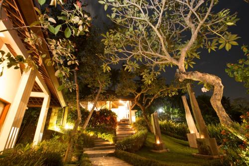a house with a garden at night with lights at The Samara Villas & Restaurant in Ubud