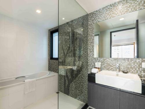 a bathroom with a tub and a sink and a mirror at Maitria Hotel Sukhumvit 18 Bangkok – A Chatrium Collection in Bangkok