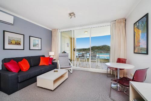 a living room with a couch and a table at Ettalong Beach Luxury Apartments in Ettalong Beach
