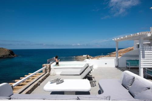 a patio with white furniture and the ocean at Merchia Bay Villas Mykonos in Merchia Beach