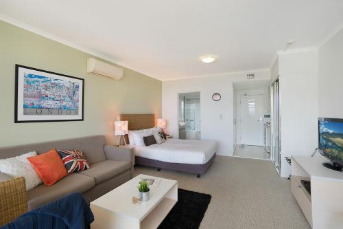 a living room with a couch and a bed at Ettalong Beach Luxury Apartments in Ettalong Beach