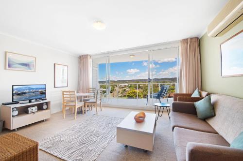 a living room with a couch and a tv and a table at Ettalong Beach Luxury Apartments in Ettalong Beach