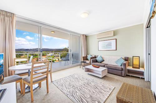 a living room with a couch and a table at Ettalong Beach Luxury Apartments in Ettalong Beach