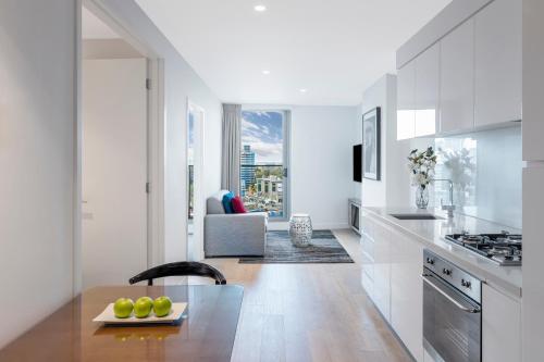 a kitchen with white cabinets and a table with fruit on a plate at Imagine Marco in Melbourne