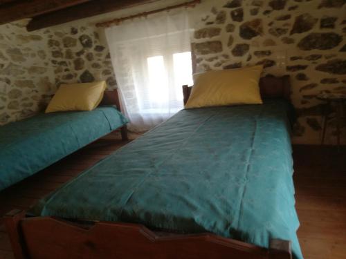 a bedroom with two beds in a stone wall at The Rock in Kapetanianá