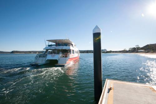 a boat on the water next to a dock at Ettalong Beach Luxury Apartments in Ettalong Beach