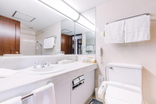 a white bathroom with a sink and a mirror at Okura Garden Hotel Shanghai in Shanghai