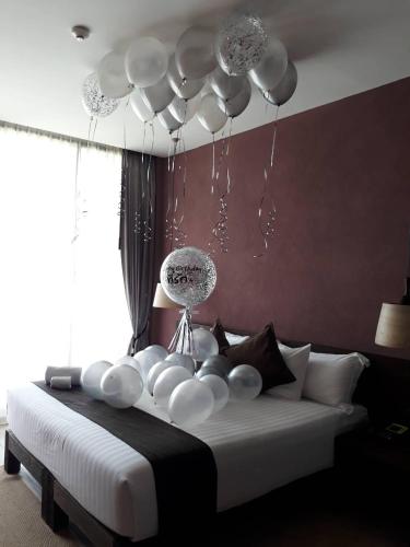 a bedroom with a white bed with a chandelier at The Glory River Kwai Hotel in Kanchanaburi