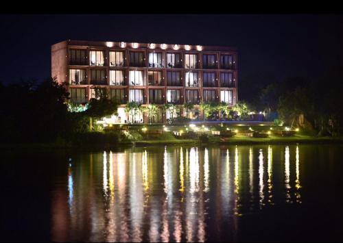 a large building with lights on the water at night at The Glory River Kwai Hotel in Kanchanaburi