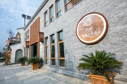 a building with a sign on the side of it at Floral Hotel · Yingxi Riverside Deqing in Deqing