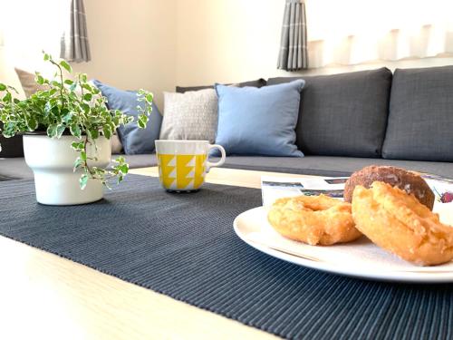 a table with a plate of donuts and a cup of coffee at Liaison House Universal Gateway in Osaka