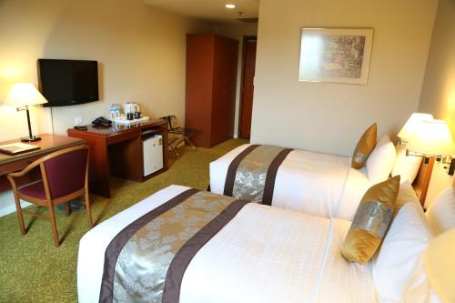 a hotel room with two beds and a desk at Summit Parkview Yangon in Yangon