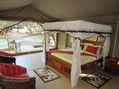 a bedroom with a canopy bed in a tent at Enchoro Wildlife Camp in Ololaimutiek