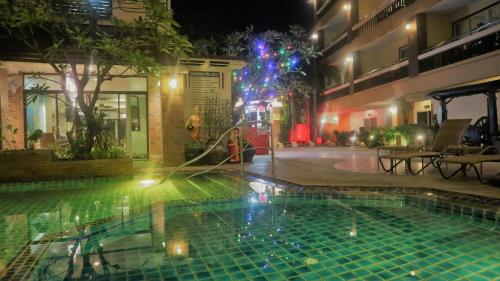 a swimming pool at night with a fountain at Aiyaree Place Hotel SHA PLUS in Jomtien Beach