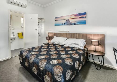 a bedroom with a large bed and a table at Rest Motels in Naracoorte