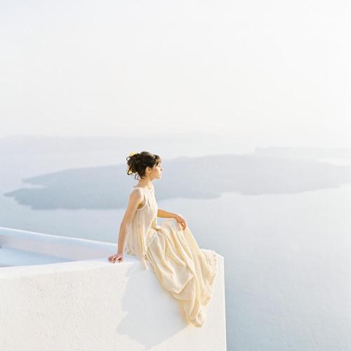 a woman in a white dress sitting on a ledge at Vallais Villa in Imerovigli