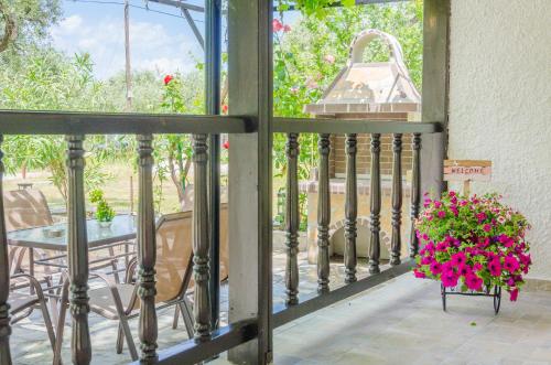 a balcony with a table and a flower basket with pink flowers at Chrisella Villa in Skala Rachoniou