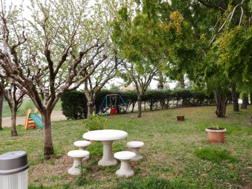 a white table and chairs in a park with trees at B&B da Eli in San Pietro