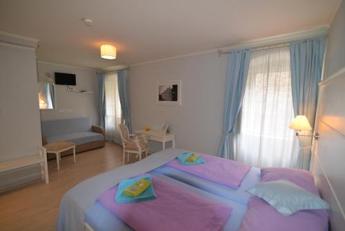 a bedroom with a large bed and a living room at Hotel Villa Elisabeth - Veli Lošinj Health Resort in Veli Lošinj