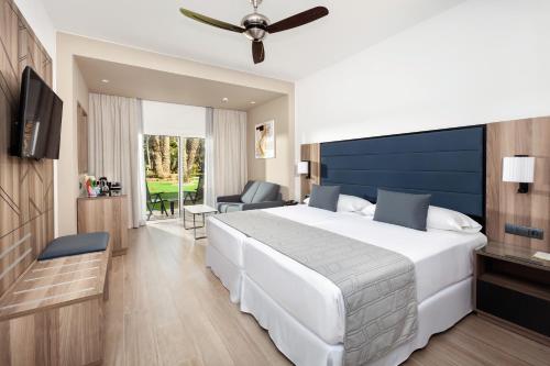 a bedroom with a large white bed with a blue headboard at Hotel Riu Palace Oasis in Maspalomas