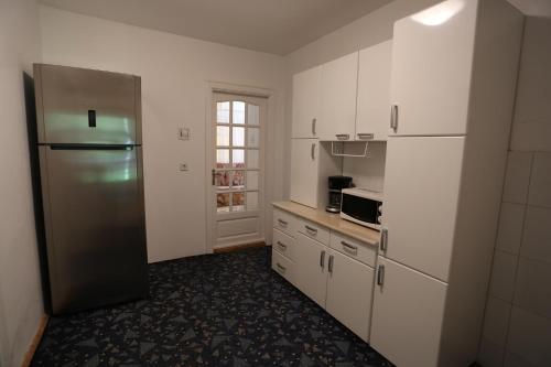 a kitchen with white cabinets and a stainless steel refrigerator at Casuta cu Zorele in Martinie
