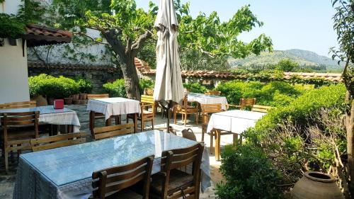 restauracja na świeżym powietrzu ze stołami i parasolem w obiekcie Nilya Hotel w mieście Selçuk