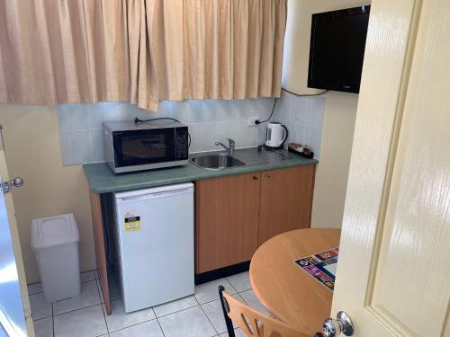 a kitchen with a microwave and a sink at John Oxley Motel in Port Macquarie