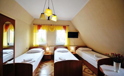 een kamer met 2 bedden en 2 ramen bij Dworek Familijny in Kołobrzeg