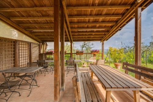 a patio with wooden tables and chairs and benches at Podere Casanova in Montespertoli