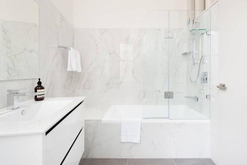 baño blanco con ducha y lavamanos en STUNNING SYDNEY HOME 4 en Sídney