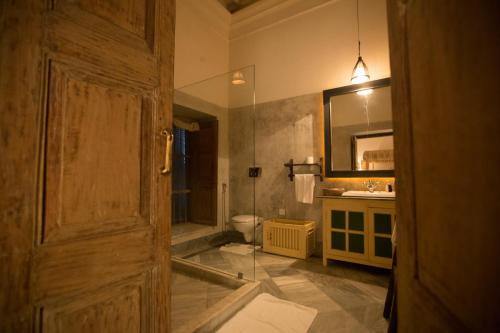 a bathroom with a toilet and a sink and a door at The Rajbari Bawali in Kolkata