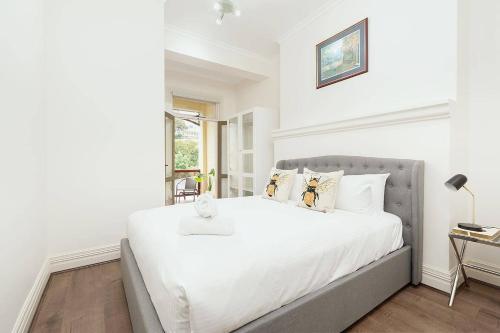 a white bedroom with a large bed with white sheets and pillows at STUNNING SYDNEY HOME 6 in Sydney