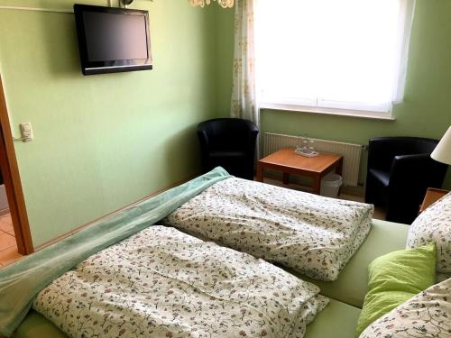 a room with a bed with pillows and a tv at Hotel garni Zum Adenauer Forst in Wimbach