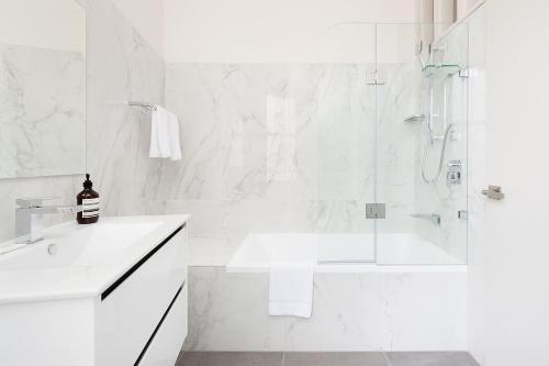 baño blanco con ducha y lavamanos en STUNNING SYDNEY HOME 9 en Sídney