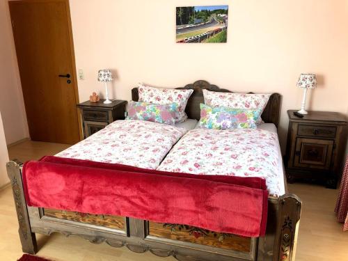 a bed with a red blanket and pillows on it at Hotel garni Zum Adenauer Forst in Wimbach