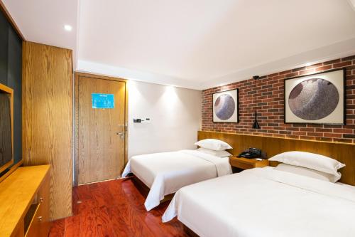 a hotel room with two beds and a brick wall at Floral Hotel · Yingxi Riverside Deqing in Deqing
