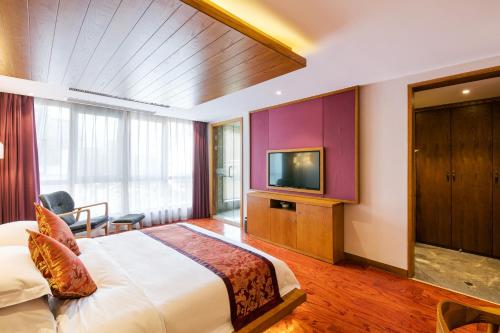 a hotel room with a bed and a tv at Floral Hotel · Yingxi Riverside Deqing in Deqing