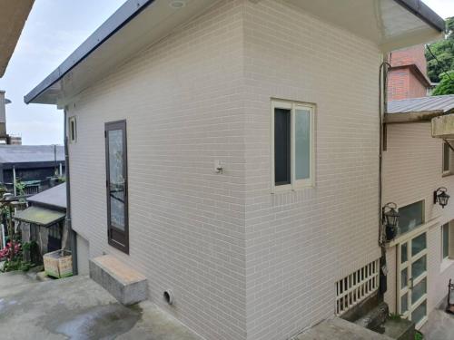 biały ceglany budynek z oknem w obiekcie Chien Ching B&B w mieście Jiufen