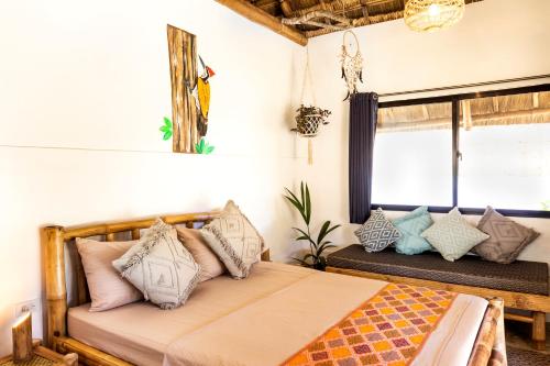 a bedroom with a bed with pillows and a window at Three Little Birds Resort in Anda