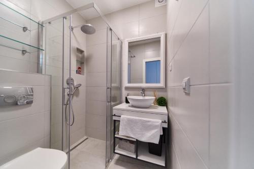 een witte badkamer met een wastafel en een douche bij Villa Baronessa in Zadar