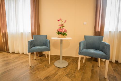 two chairs and a table with a vase of flowers at Hotel Mar Garni in Belgrade